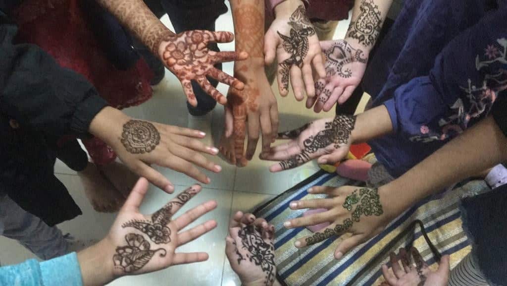 Womens' hands are painted with henna.