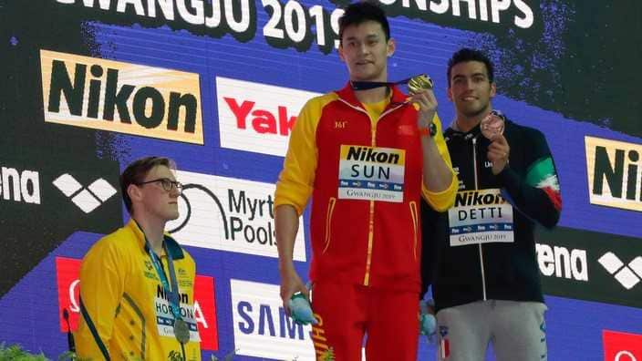 China's Sun Yang, holds up his gold medal as silver medalist Australia's Mack Horton, stands away from the podium