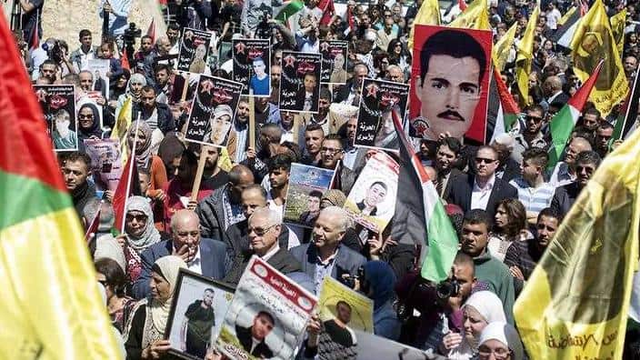 Palestinian family members hold pictures of their relatives, jailed in Israeli prisons