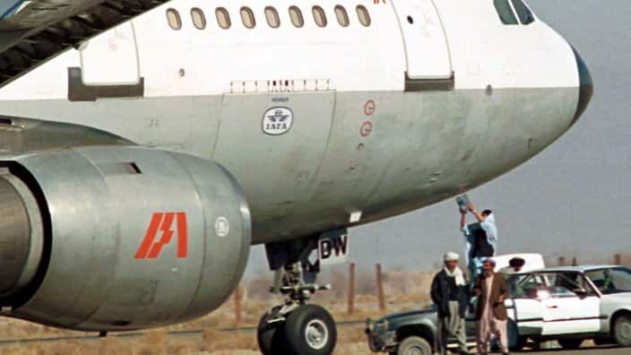 A Taliban soldier hands over a bottle of locally filled water to someone inside the hijacked Indian Airlines plane Tuesday, Dec. 28, 1999 at the Kandahar airport in Afghanistan. 