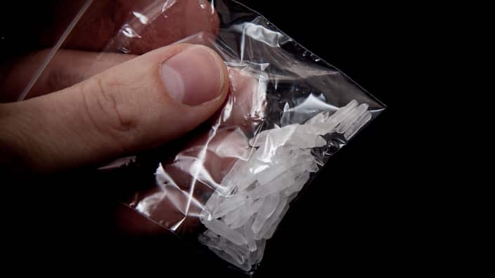 Cropped Image Of Hand Holding Methamphetamine Against Black Background