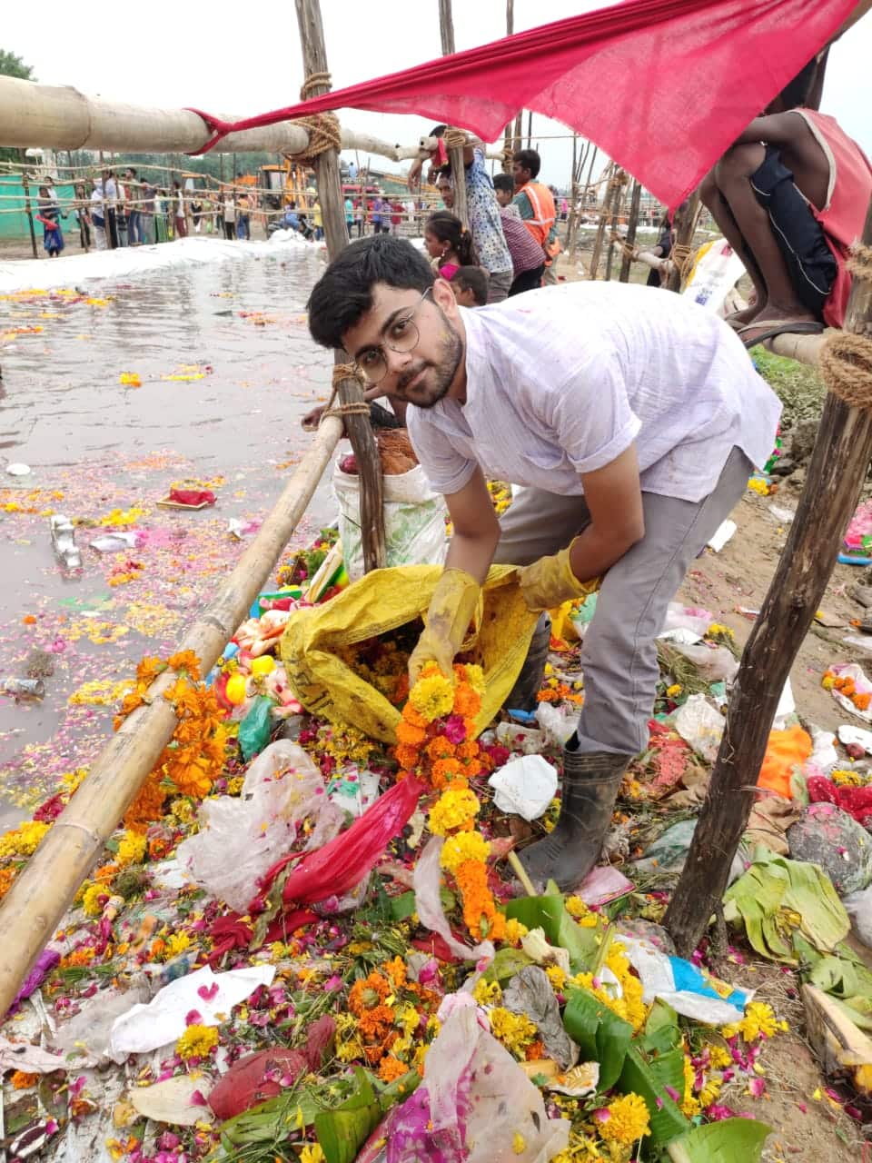 21 year old Yash Bhatt collects flowers disposed off after being offered at the temples