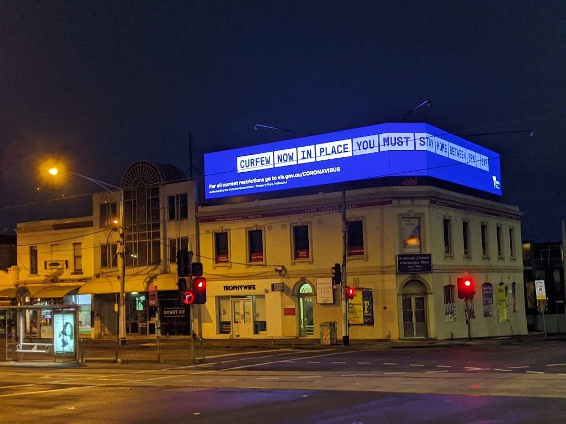 Un'immagine dei cartelloni luminosi allestiti nel centro di Melbourne per ricordare ai cittadini che il coprifuoco era in vigore