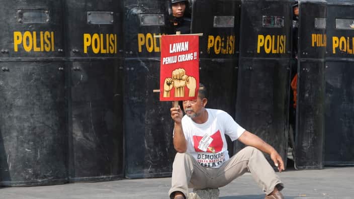 A Muslim activist holds a placard reading 'cheating election opponents' during a mass rally following the announcement of election results in Jakarta, Indonesia, 21 May 2019.