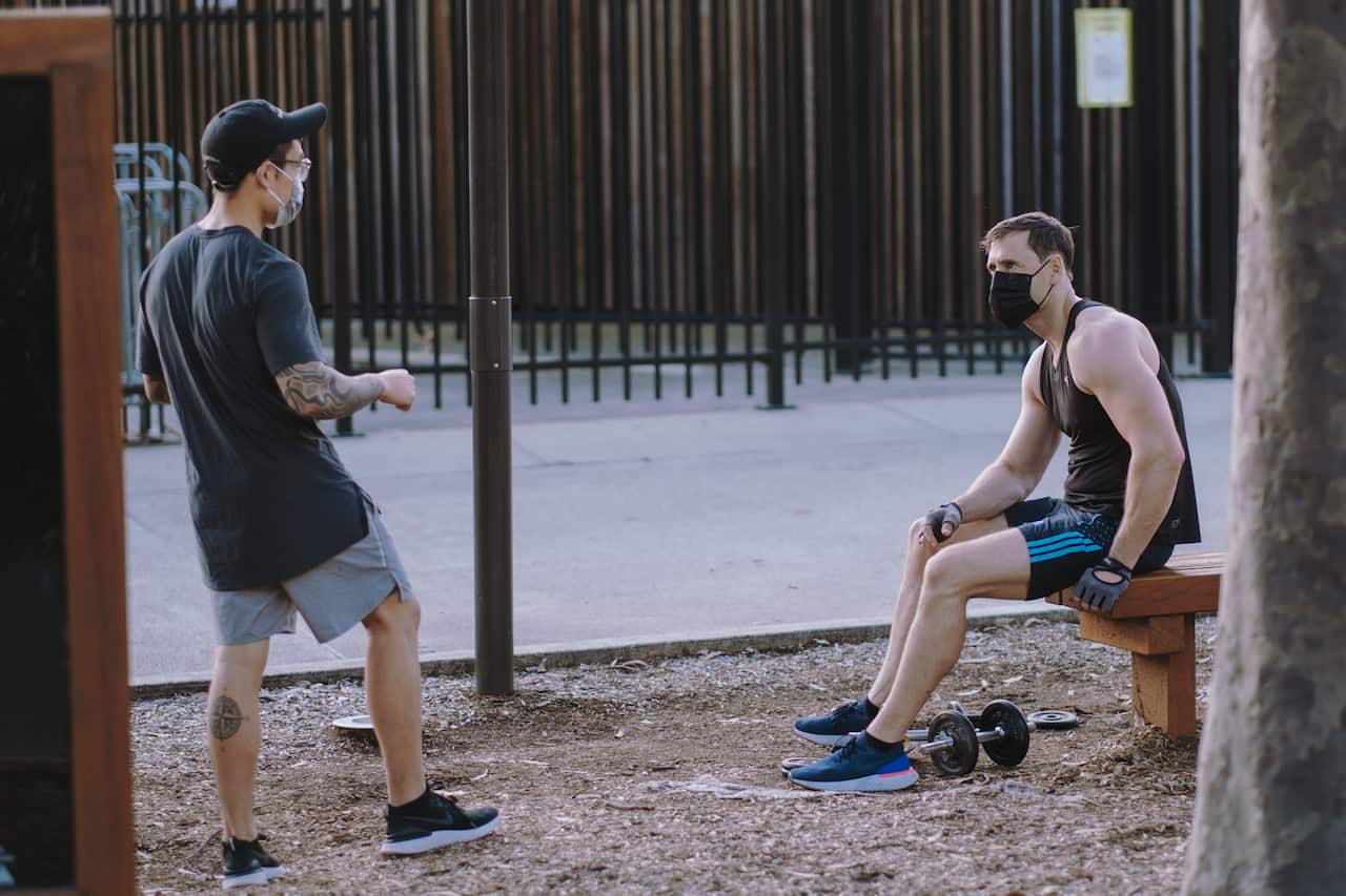 Two men in face masks working out in the park during a coronavirus lockdown