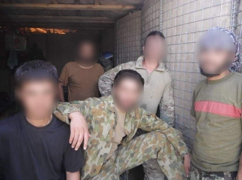 Khalid* (front, centre) with an Australian soldier (behind, centre) and Khalid's family members.