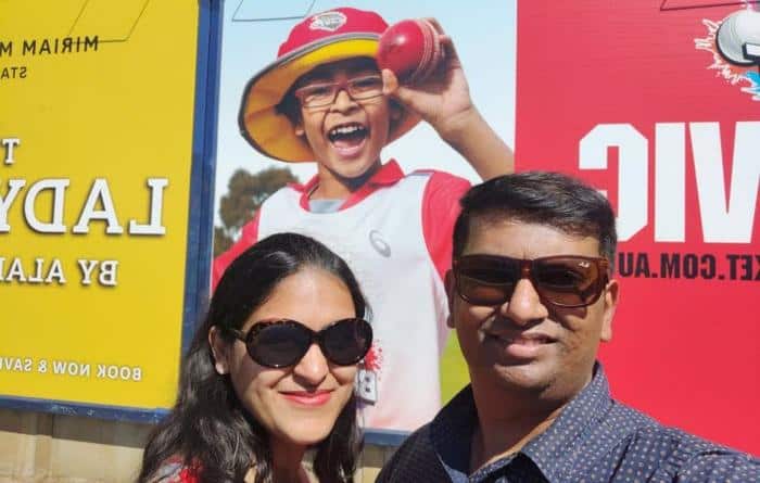 Soniya Khandelwal and Atul Khandelwal posing with their son's hoarding in Melbourne