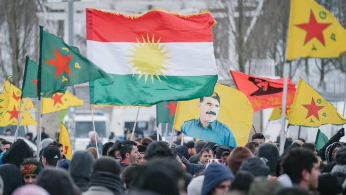 People wave the Kurdish flags and the Kurdish People's Protection Units (YPG) flags during a march against the ongoing Turkish military offensive