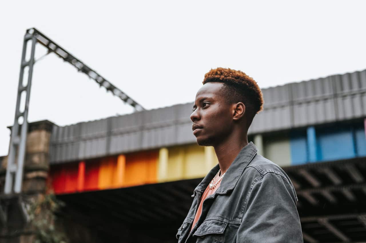 A young man staniding near building with lgbt graffiti