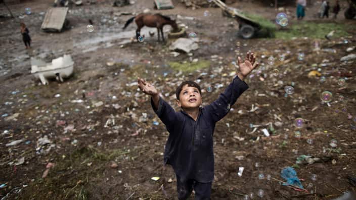 Zawar Khan, an Afghan refugee child chases bubbles released by other children while playing on the outskirts of Islamabad, Pakistan