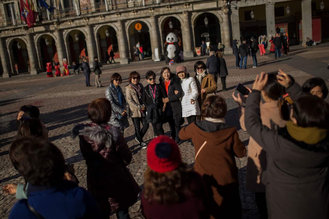 Tourists pose for a photograph at the Mayor square in central Madrid, Thursday, Jan. 11, 2018. Spain says it has broken its record of international visitors for the fifth consecutive year in 2017 with 82 million tourists that chose restive Catalonia as th