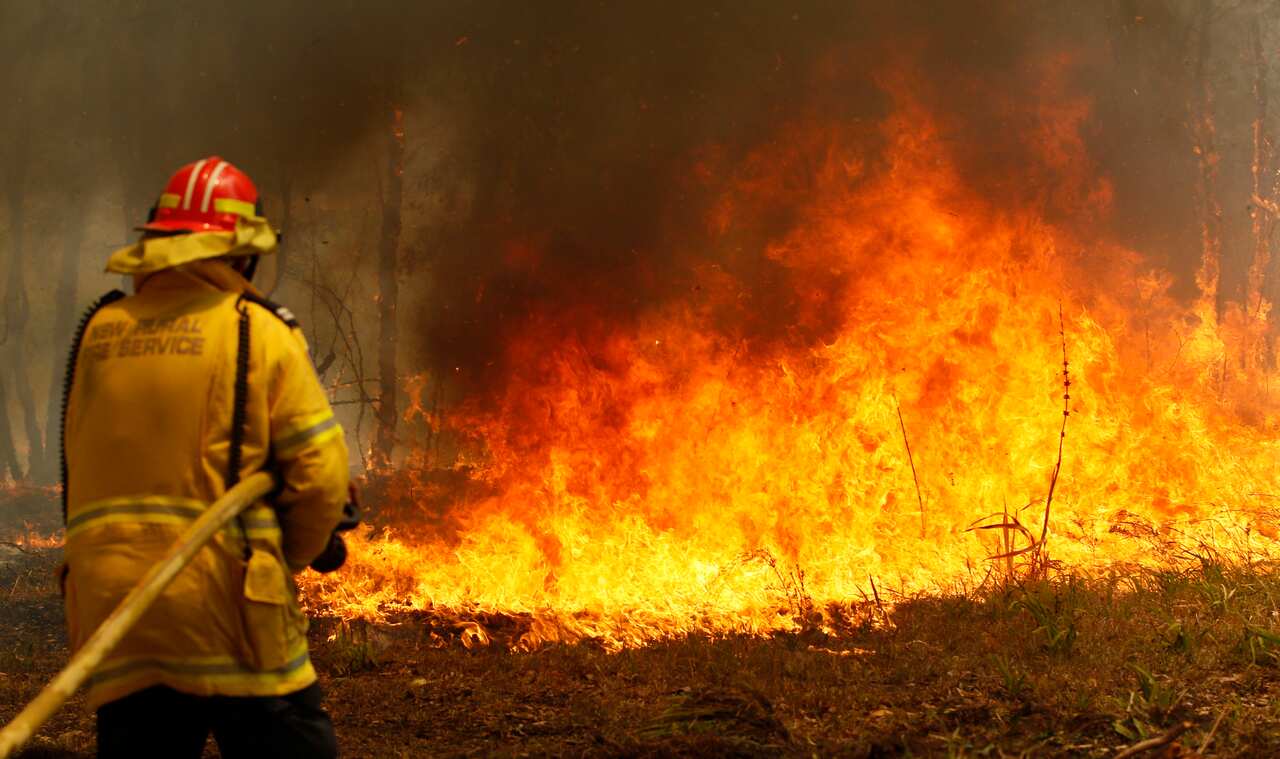 Firefighters work to contain a bushfire along Old Bar road in Old Bar, NSW, Saturday, November 9, 2019. 