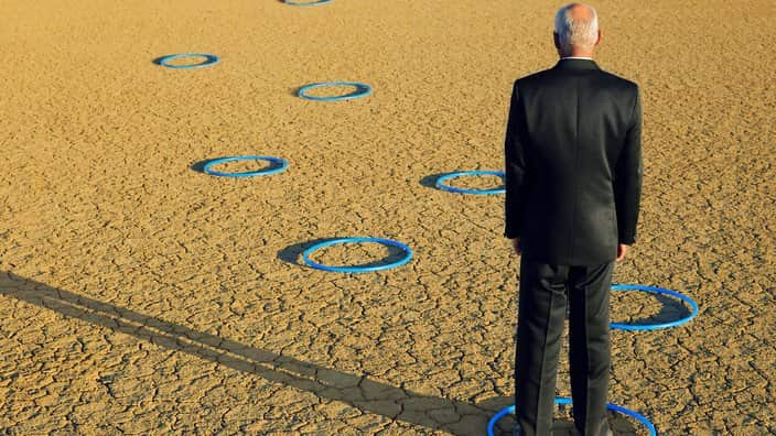 Businessman standing in hoops in desert back view full length