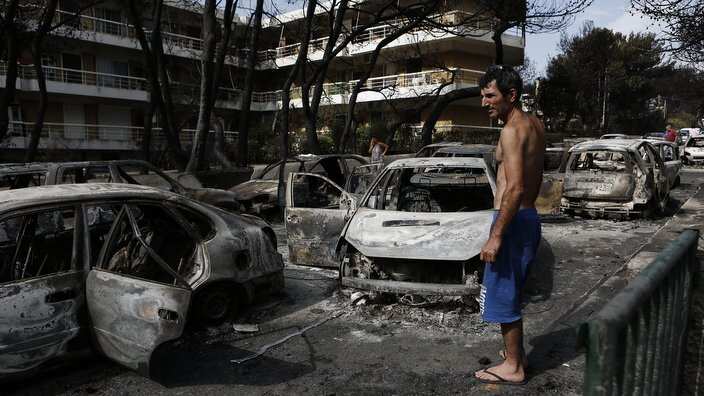 A man looks at burned cars following a forest fire in Mati a northeast suburb of Athens, Greece.