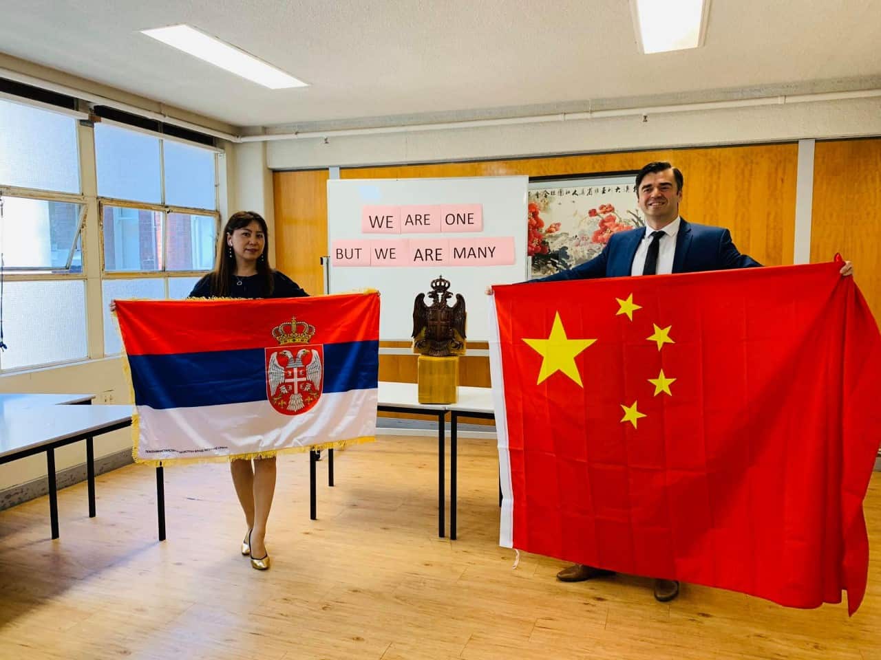 Ms Junxi Su and Mr Slobodan Bendjo proudly hold each others' national flag. 