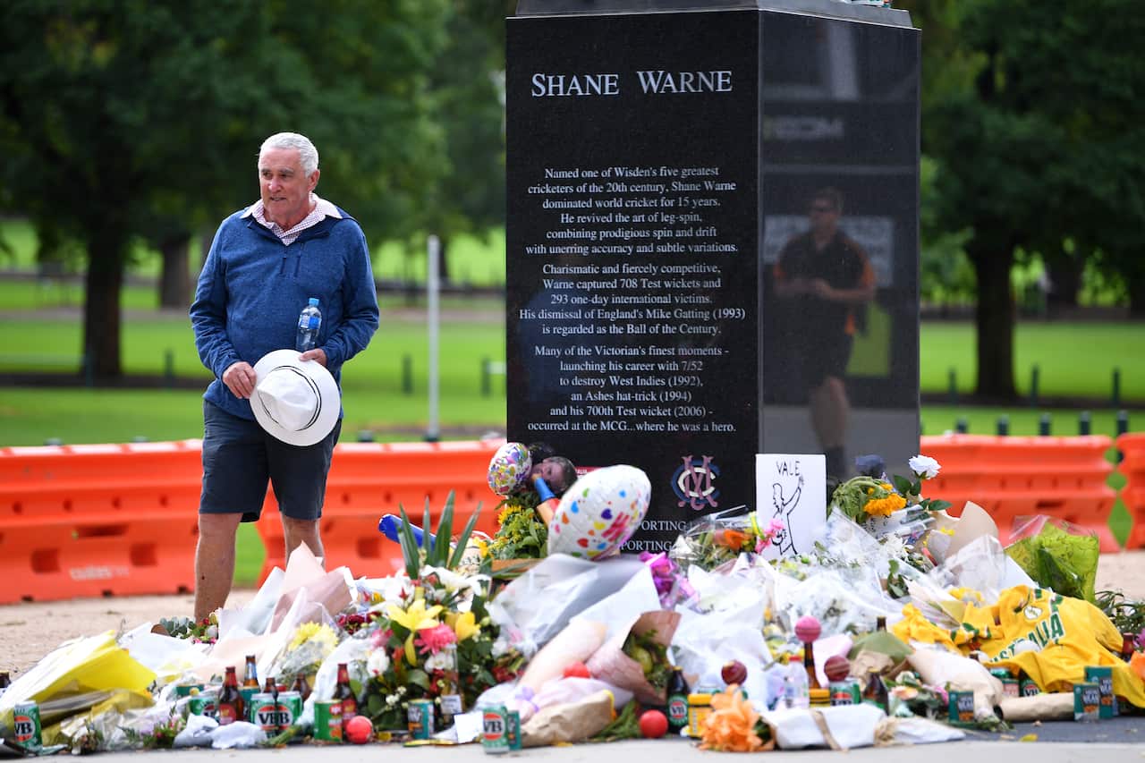 A person observes tributes to Australian cricketer Shane Warne at his statue outside the MCG in Melbourne.