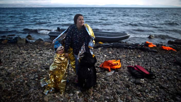 A Syrian refugee woman and child are wrapped with thermal blankets to shelter from the cold after arriving on a dinghy from the Turkish coast to the northeastern Greek island of Lesbos, October 2015