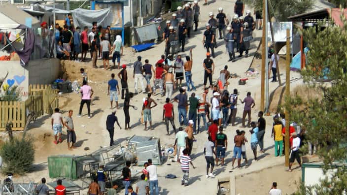 Migrants argue with riot police in the camp of Moria on Lesvos island