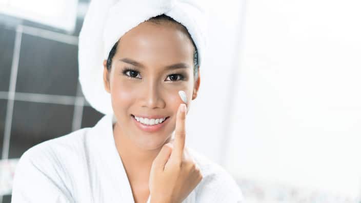 Asian women are applying cream and lotion to her face after bathing in the bathroom.