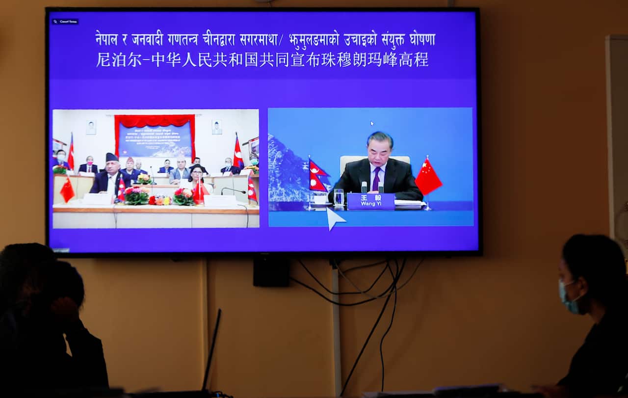 Nepalese government officers watch a live telecast of a joint announcement on the height of Mount Everest, in Kathmandu, Nepal, Tuesday, Dec. 8, 2020. China and Nepal have jointly announced on Tuesday, Dec. 8, 2020