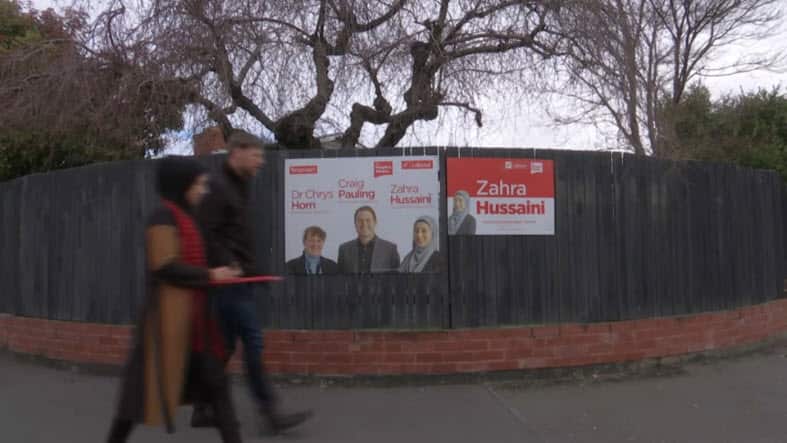 Ms Hussaini walks past promotional material for her campaign.