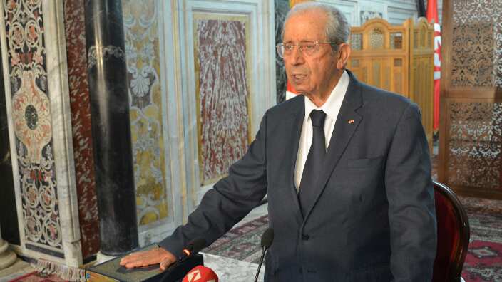 Tunisian parliament president Mohamed Ennaceur, puts his hand on the Quran to be sworn in as Tunisian interim President in Tunis