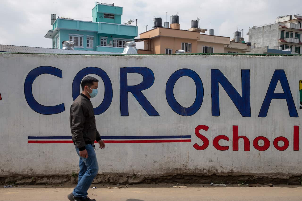A man wearing facial mask walks in front of Corona School during a emergency nationwide lock down in Kathmandu, Nepal, 24 March 2020. 
