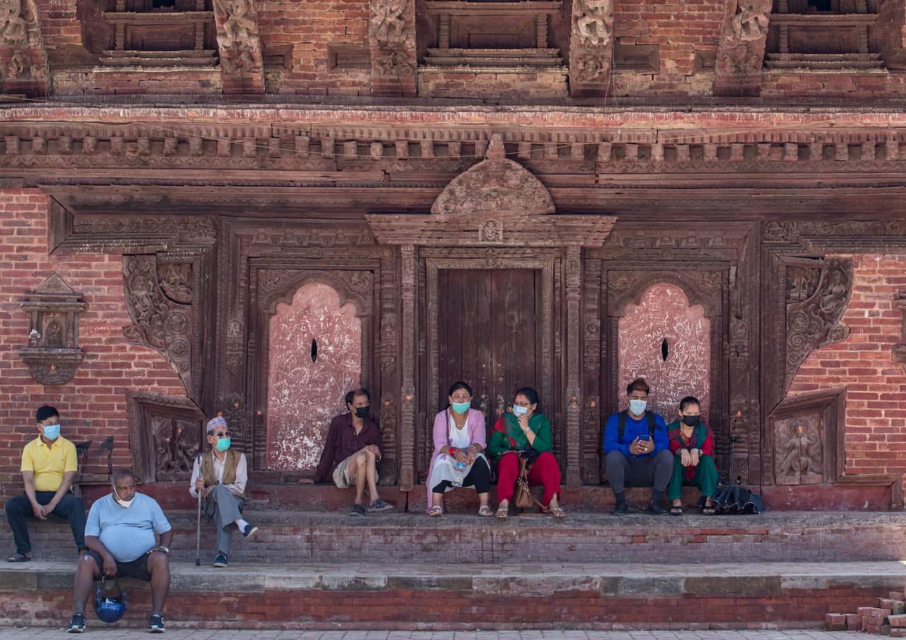 Nepalese people wear facial mask as they watch in Kathmandu, Nepal, 04 August 2020.