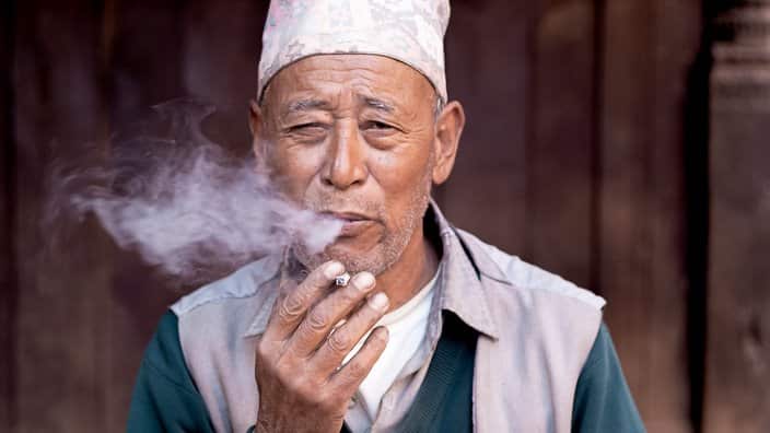 Old Nepali man smoking a cigarette.