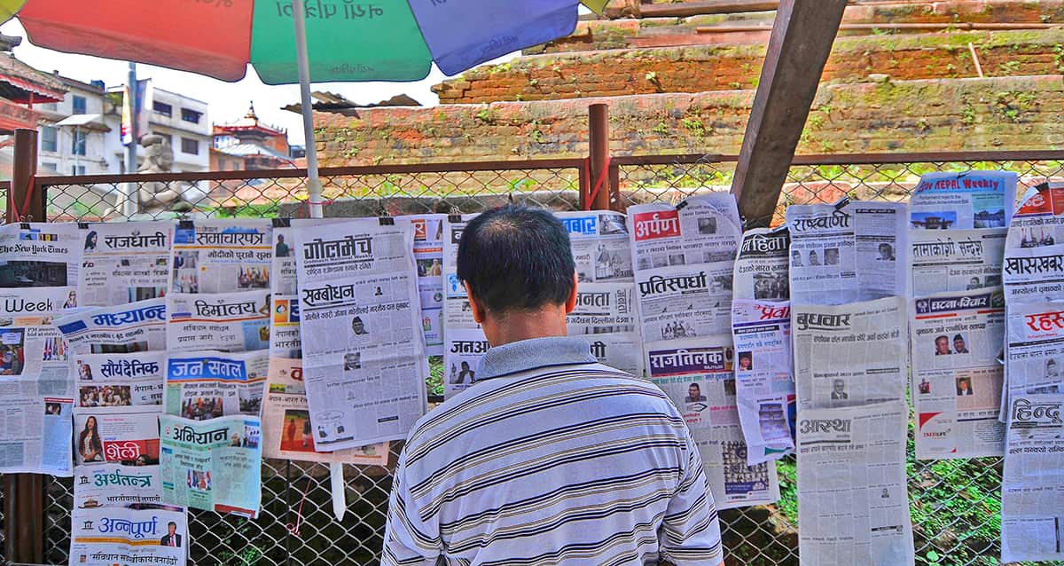 A man reading highlights of front page cover news on the daily paper at Basantapur Durbar Square, Kathmandu, NEPAL.