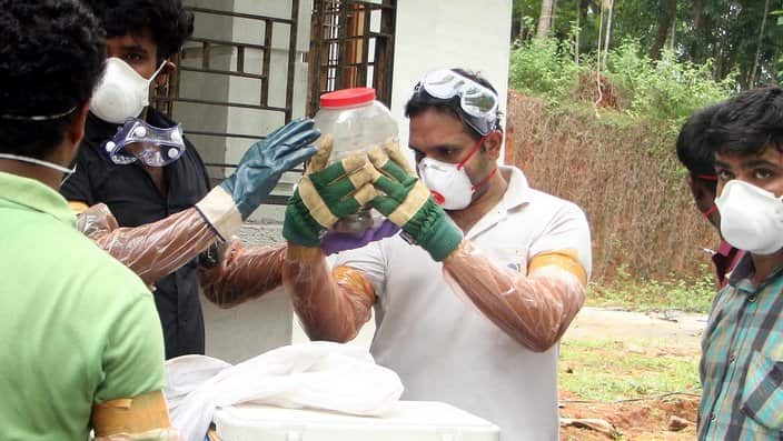 Indian animal husbandry department and forest officials look at a bat kept in a container after catching it from a well at Changaroth in Kerala.