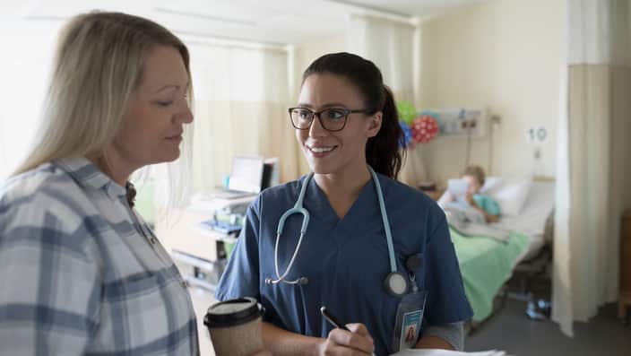 Nurse discussing medical record with mother of boy patient in hospital