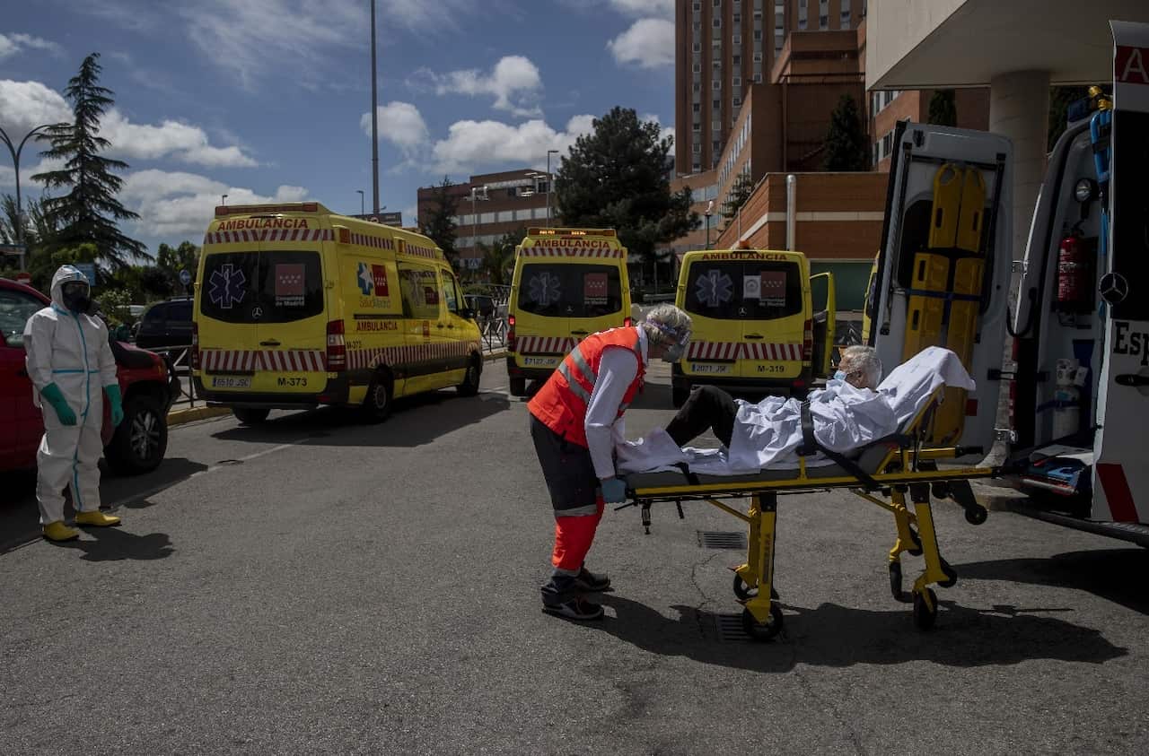 An emergency worker wearing a face mask transports an elderly patient to an ambulance at the 12 Octubre hospital in Madrid, Spain.