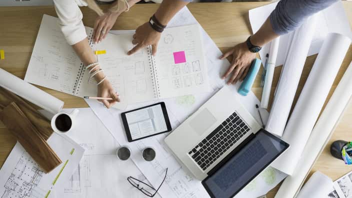 Overhead view architects drafting blueprints at table