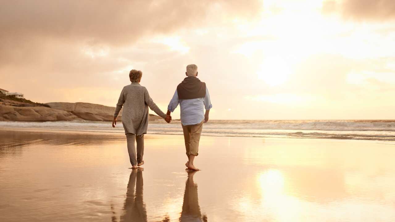 Older couple holding hand on beach