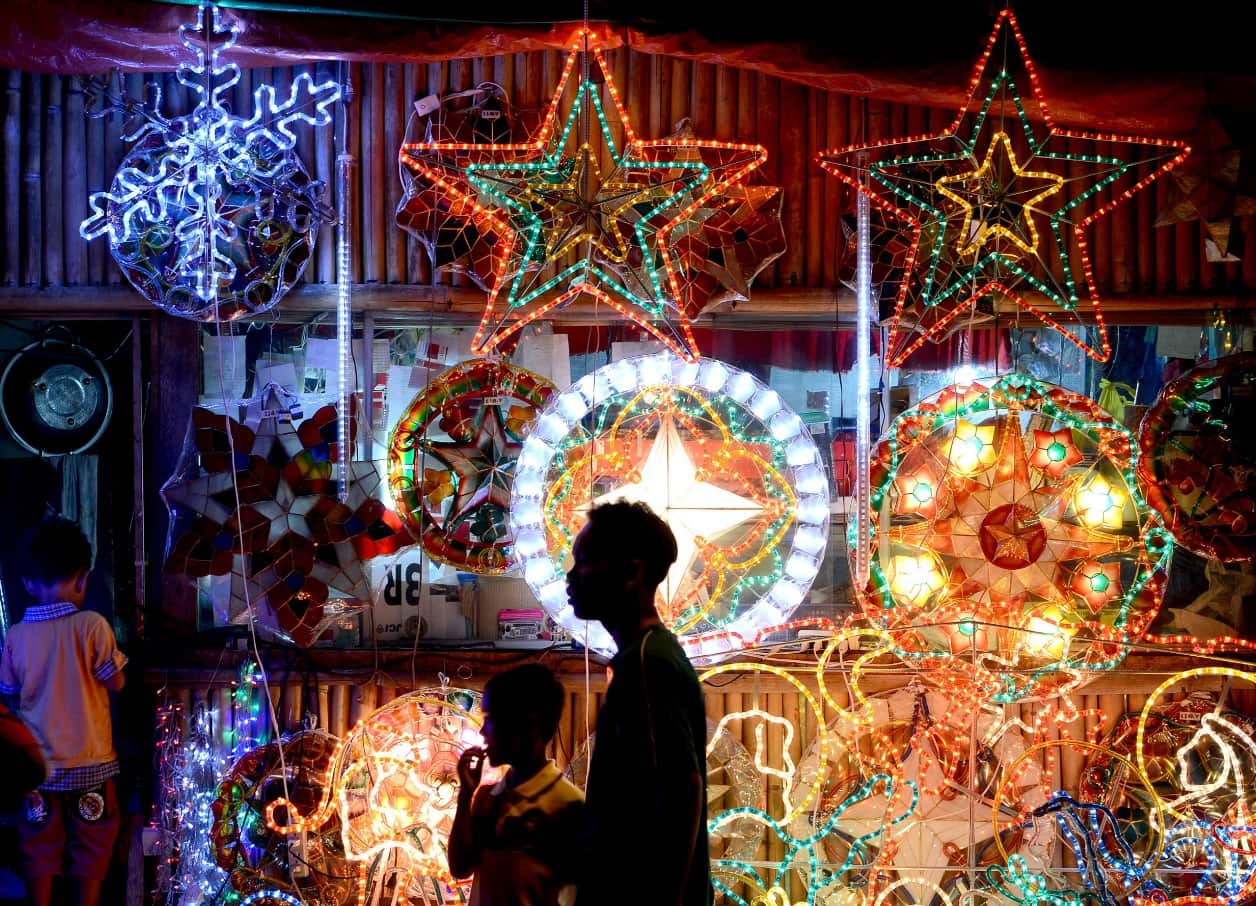 Buyers stand in front of lanterns known locally as 'parol' on display along a street in Manila