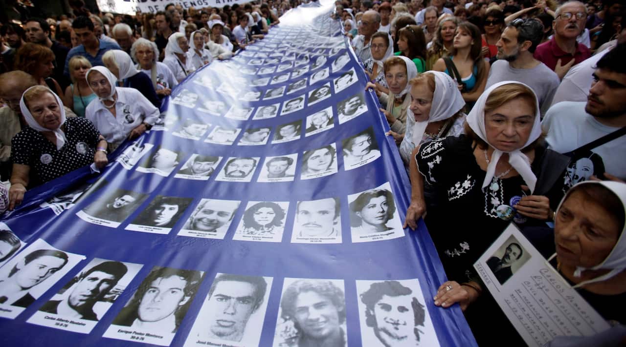 Members the Argentinian Grandmothers of the Plaza de Mayo and Mothers of the Plaza de Mayo, carrying a banner with images of people missing