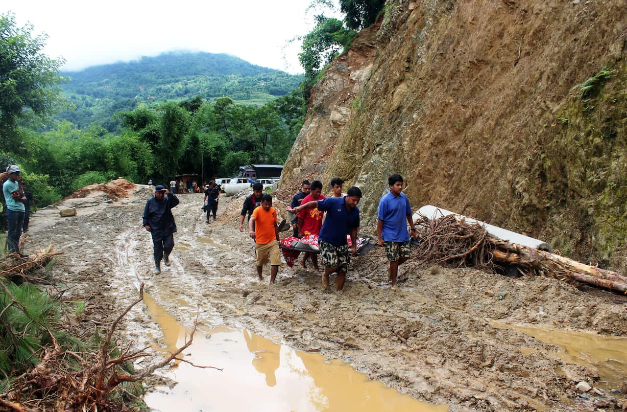 People carrying a women, who went on labor,  on a stretcher after a road was blocked by a landslide in Galkot, Nepal