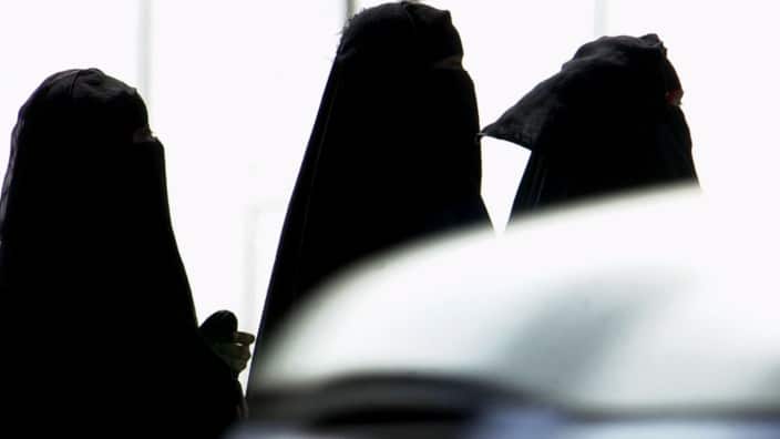 Saudi women walk past cars in a Riyadh, Saudi Arabia