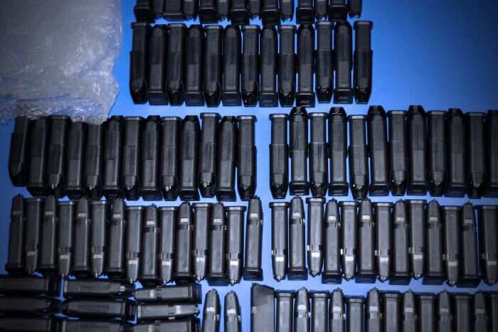 Dozens of Glock pistol magazines are lined up on a blue table