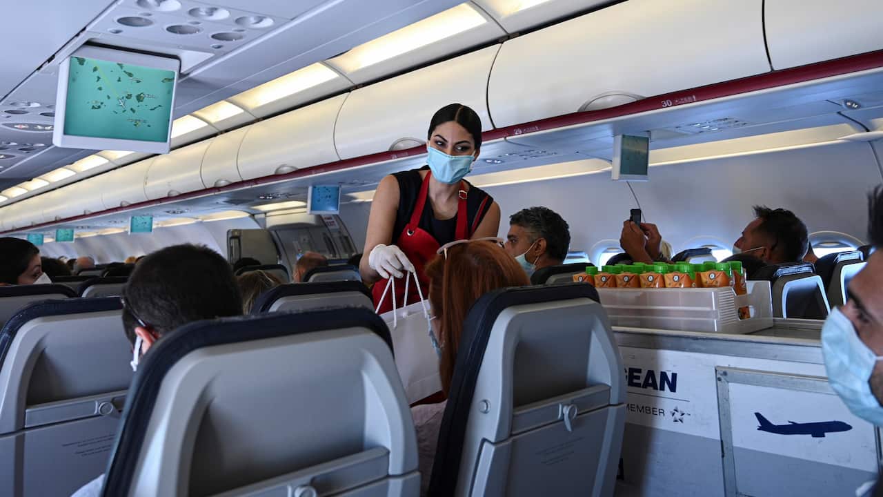 cabin crew member in protective gear serving passengers