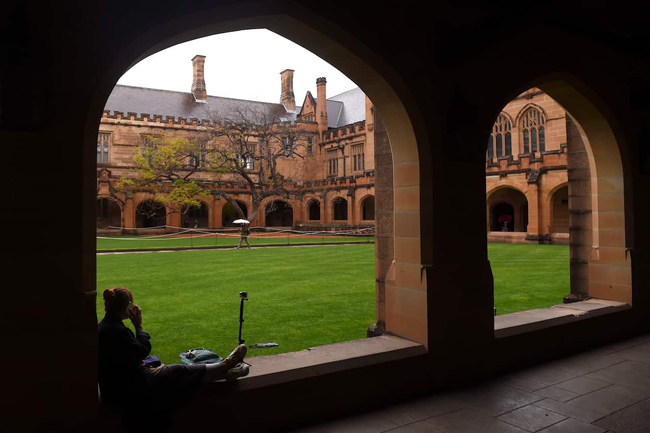A student sits next to the quadrangle at the University of Sydney.