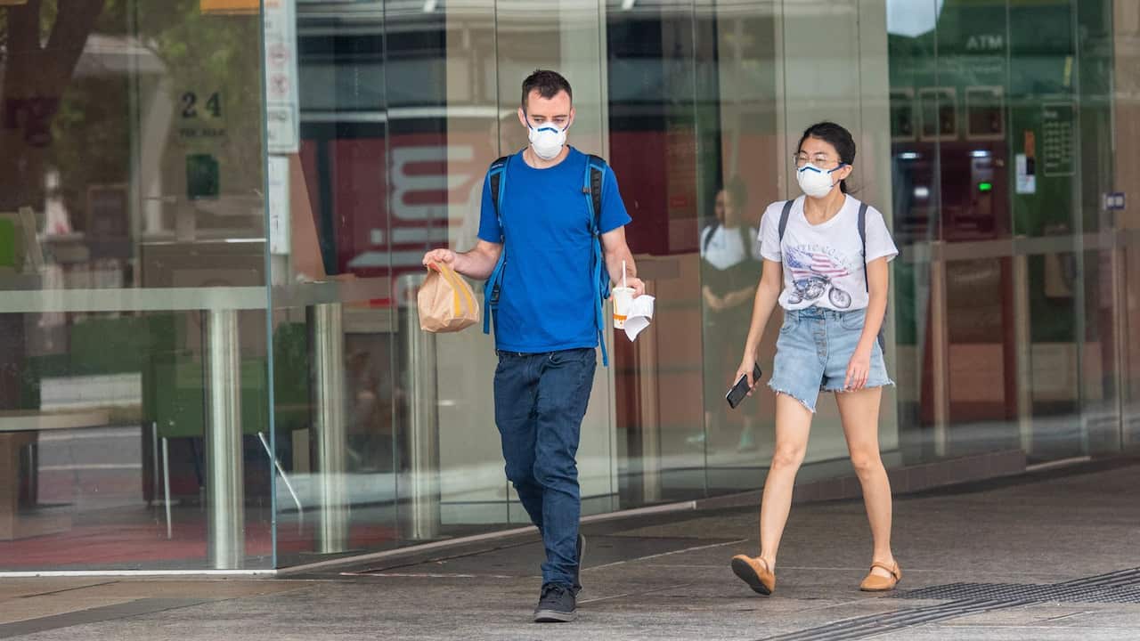 A couple wear face masks as a precaution against the spread of Coronavirus in Brisbane..Covid-19 pandemic hits Australian capital cities. Sports, music events are cancelled or postponed and school, universities and business follow government guidelines ab