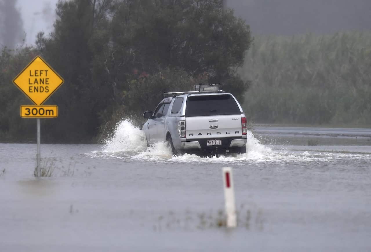A car drives through a flooded road at Tumbulgum, NSW, Monday, Southeast Queensland and coastal NSW is set to recieve more than 200mm of rain
