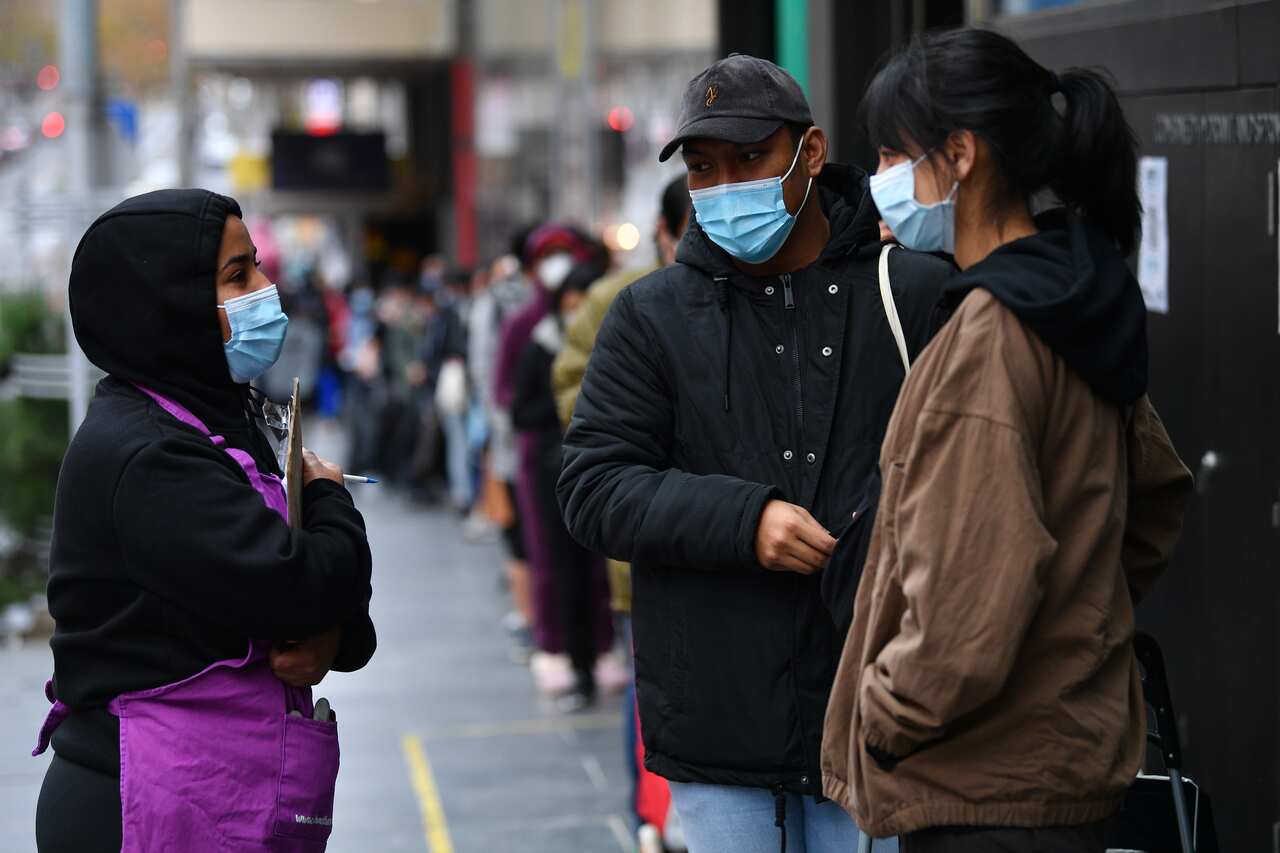 A Foodbank staff member speaks with international students waiting in a line outside of the Foodbank pop up store in Melbourne, Friday, June 4, 2021. 
