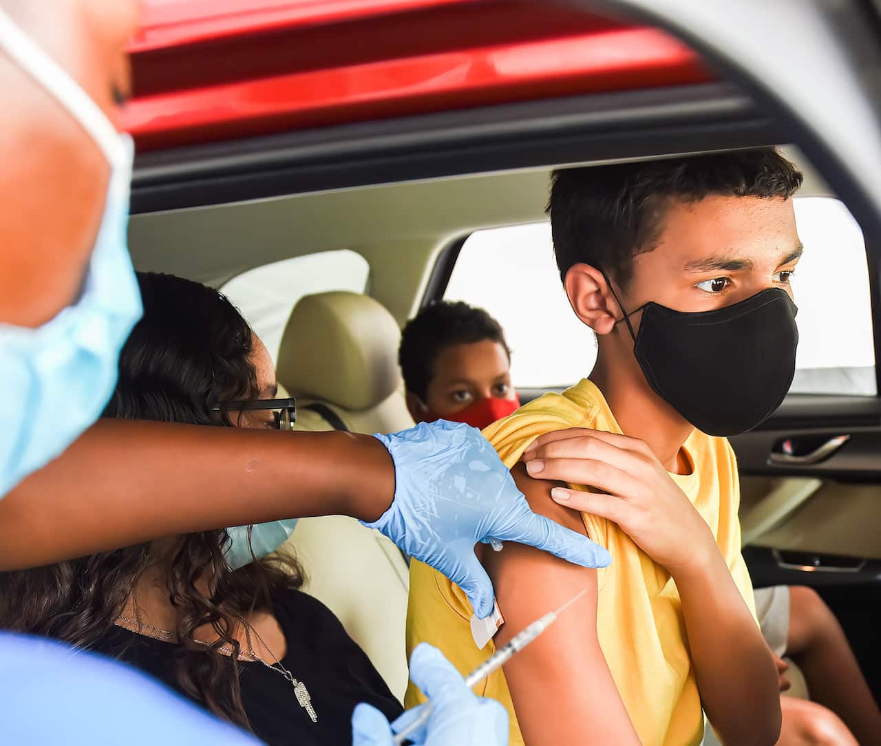 A nurse administers a COVID-19 vaccine to a kid at a drive-thru COVID-19 testing and vaccination site at Barnett Park in Orlando