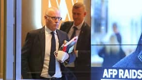 Executive Editor of ABC News John Lyons is followed by an Australian Federal Police officer as they leave the office after the raid.