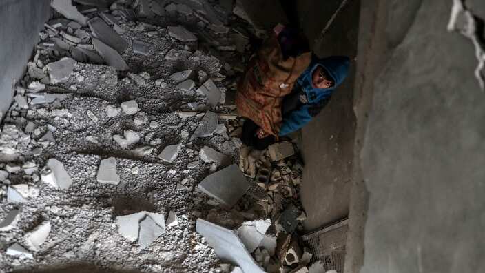 A boy inspects the rubble of a damaggot killed in Douma