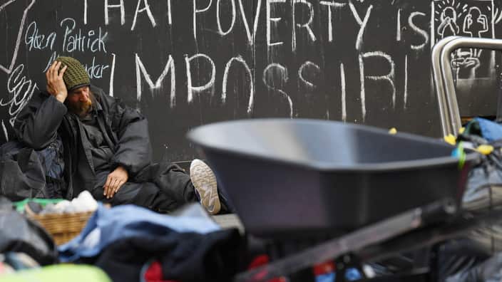 A homeless man sits on the ground as others pack away their belongings and prepare to leave Tent City in Martin Place in Sydney, Friday, August 11, 2017. (AAP Image/David Moir) NO ARCHIVING