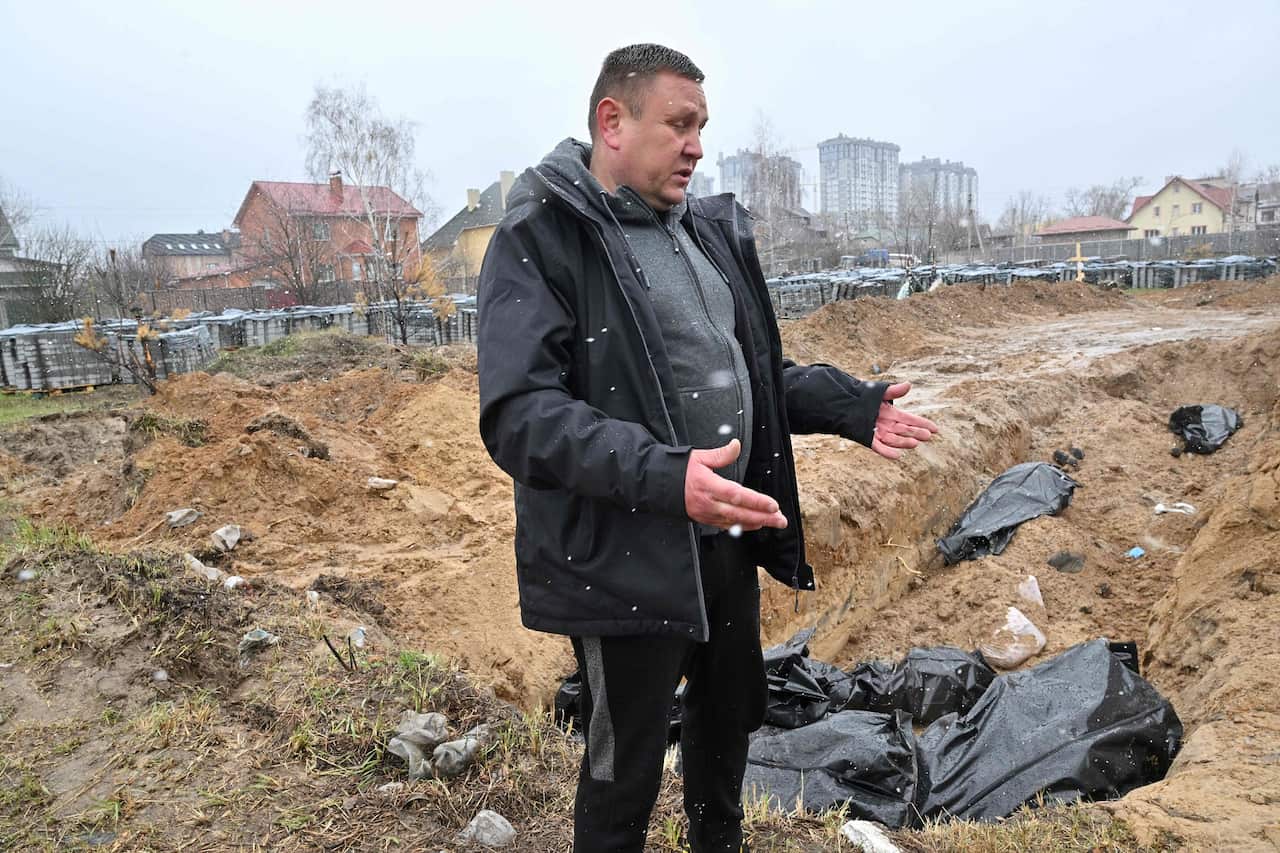 A man gestures at a mass grave in the town of Bucha, northwest of the Ukrainian capital Kyiv on April 3, 2022Photo by Sergei SUPINSKY / AFP) (Photo by SERGEI SUPINSKY/AFP via Getty Images)